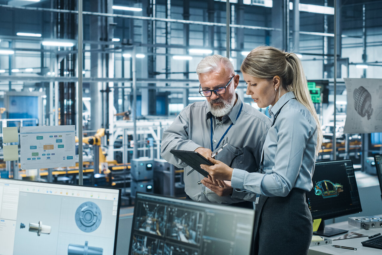 Zwei Fachkräfte analysieren digitale Produktionsdaten auf einem Tablet in einer modernen Fertigungsumgebung zur Bewertung von Softwarelösungen und digitalen Anwendungsfällen.