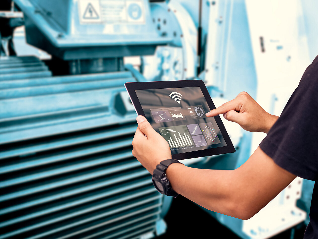 Mitarbeiter in Fertigungshalle prüft Echtzeit-Prozessdaten und Kennzahlen auf einem Tablet vor Industriemaschine