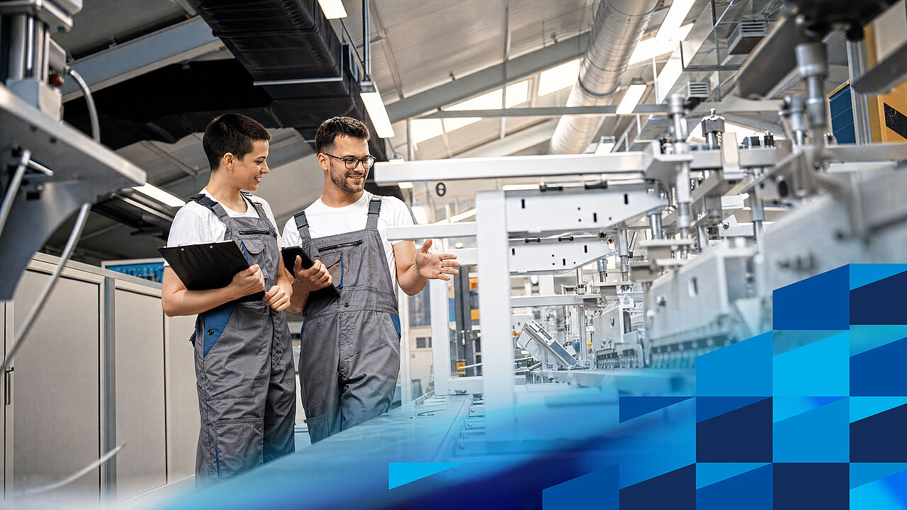 Zwei Fachkräfte analysieren Prozesse und Produktionsdaten an einer automatisierten Fertigungslinie.